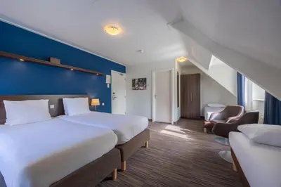 a hotel room with a large bed and a blue wall at Amrâth Hotel Media Park Hilversum in Hilversum