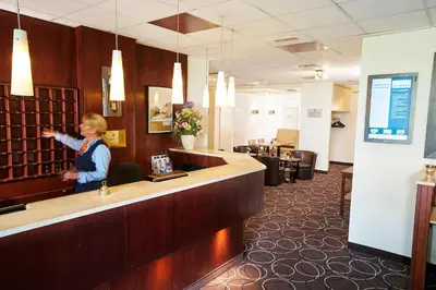 a woman standing at a counter in a waiting room at Amrâth Hotel Media Park Hilversum in Hilversum