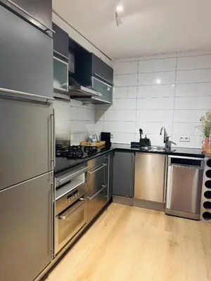 a large kitchen with stainless steel appliances and wooden floors at Hello Noordwijk - Souterrain Hoogwakersbosstraat 6 in Noordwijk aan Zee