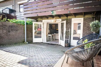 a patio with a white door and a table and chairs at Hello Noordwijk - Souterrain Hoogwakersbosstraat 6 in Noordwijk aan Zee
