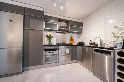 a kitchen with stainless steel appliances and cabinets at Hello Noordwijk - Souterrain Hoogwakersbosstraat 6 in Noordwijk aan Zee