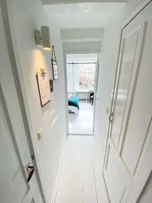 a white hallway with an open door at JoyJoyJoy the Green Palm ecolicious studio in a in historic Canalhouse from 1729 with view on the canals in Amsterdam