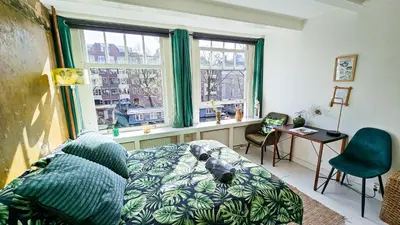 a bedroom with a dog laying on a bed in front of a window at JoyJoyJoy the Green Palm ecolicious studio in a in historic Canalhouse from 1729 with view on the canals in Amsterdam