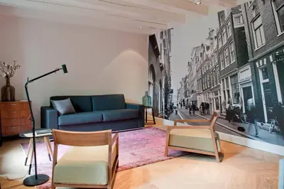 a living room with a blue couch and chairs at Hotel IX Nine Streets Amsterdam in Amsterdam