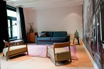 a living room with a blue couch and chairs at Hotel IX Nine Streets Amsterdam in Amsterdam