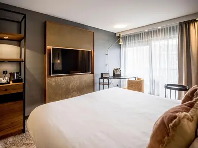 a hotel room with a bed and a tv at Alexander Hotel in Noordwijk aan Zee