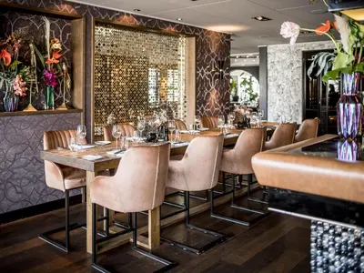 a restaurant with wooden tables and chairs and a bar at Alexander Hotel in Noordwijk aan Zee