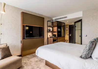 a bedroom with a large white bed and a chair at Alexander Hotel in Noordwijk aan Zee
