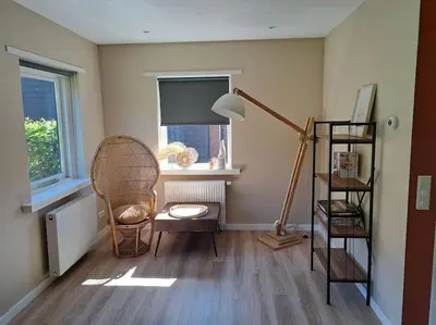 a room with a lamp and a chair and a shelf at Family House Wakker in Eemnes