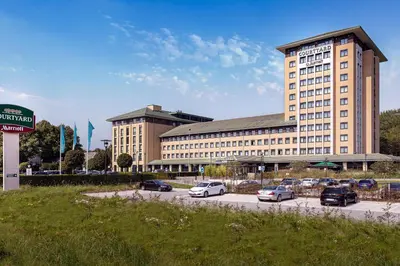 a large building with cars parked in a parking lot at Courtyard by Marriott Amsterdam Airport in Hoofddorp