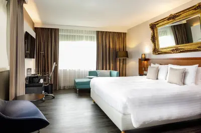 a hotel room with a large white bed and a chair at Courtyard by Marriott Amsterdam Airport in Hoofddorp