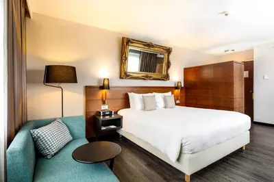 a hotel room with a bed and a couch at Courtyard by Marriott Amsterdam Airport in Hoofddorp