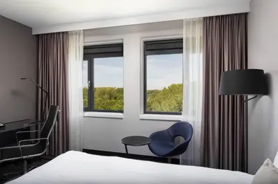a hotel room with a bed and a chair and window at Courtyard by Marriott Amsterdam Airport in Hoofddorp