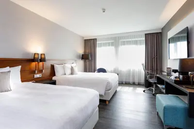 a hotel room with two beds and a desk at Courtyard by Marriott Amsterdam Airport in Hoofddorp