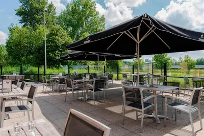 a group of tables and chairs with an umbrella at Courtyard by Marriott Amsterdam Airport in Hoofddorp