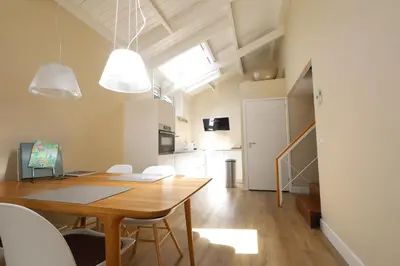 a dining room with a wooden table and white chairs at Huisje Hendrik in Baarn