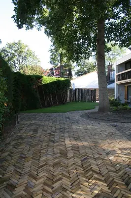 a brick driveway with a tree in the middle at Huisje Hendrik in Baarn