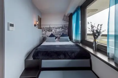 a bedroom with a bed and a large window at Palace Hotel Zandvoort in Zandvoort