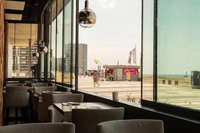 a restaurant with a view of the beach from a window at Palace Hotel Zandvoort in Zandvoort