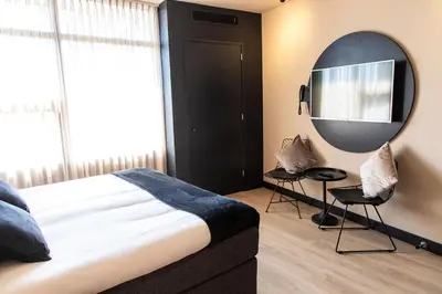 a bedroom with a large bed and a mirror at Palace Hotel Zandvoort in Zandvoort