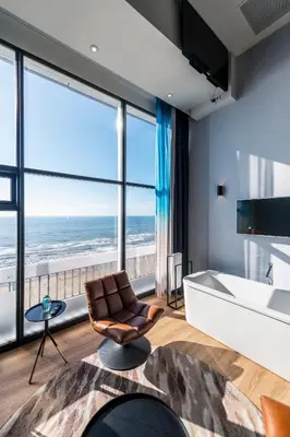 a living room with a chair and a large window at Palace Hotel Zandvoort in Zandvoort