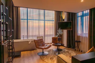 a living room with a couch and a chair and a tub at Palace Hotel Zandvoort in Zandvoort