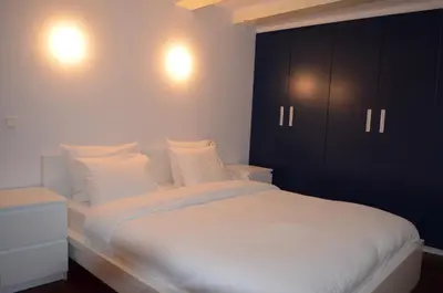 a bedroom with a large white bed with black cabinets at Rembrandtplein Bed & Breakfast in Amsterdam