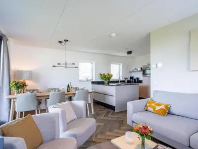 a living room and kitchen with a couch and chairs at Holiday Home Putter Comfort by Interhome in Noordwijk