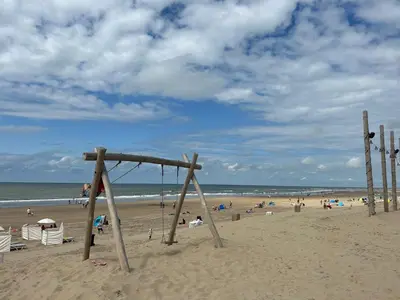 a swing set in the sand on a beach at Holiday Home Putter Comfort by Interhome in Noordwijk