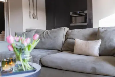 a couch with a vase of flowers on a table at Hello Noordwijk - Appartement Duindamseweg 14E in Noordwijk aan Zee