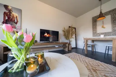 a living room with a vase of flowers on a table at Hello Noordwijk - Appartement Duindamseweg 14E in Noordwijk aan Zee