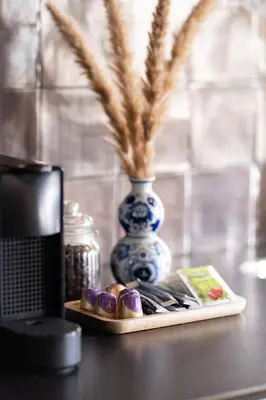 a table with a blue and white vase and a plate of food at Hello Noordwijk - Appartement Duindamseweg 14E in Noordwijk aan Zee