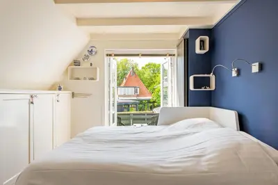 a bedroom with a white bed and a blue wall at Huize Nassau in Bergen