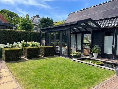 a garden with a black conservatory with green grass at Huize Nassau in Bergen