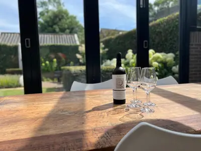 a bottle of wine sitting on a wooden table with two glasses at Huize Nassau in Bergen