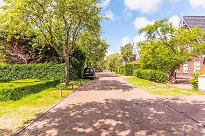 a street with trees and a car parked on the road at Huize Nassau in Bergen