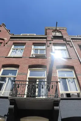 a tall red brick building with a balcony at Amsterdam Hostel Annemarie in Amsterdam