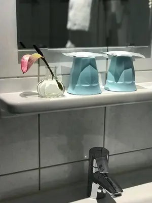 a bathroom sink with a vase with a flower in it at Hotel Luxer in Amsterdam