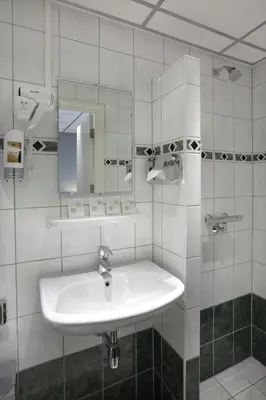 a white bathroom with a sink and a mirror at Hotel Luxer in Amsterdam