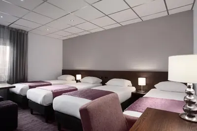 a hotel room with four beds and a table and chairs at Hotel Luxer in Amsterdam