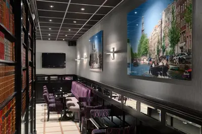 a restaurant with a bar with purple chairs and a tv at Hotel Luxer in Amsterdam