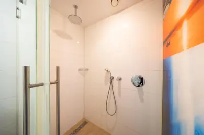 a shower in a bathroom with white tiles at Van der Valk Hotel Schiphol in Hoofddorp