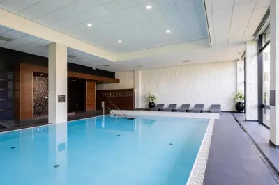 a large swimming pool in a hotel lobby with chairs at Van der Valk Hotel Schiphol in Hoofddorp