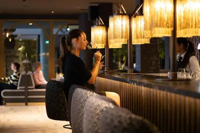 a woman sitting at a bar drinking a glass of wine at Van der Valk Hotel Vianen - Utrecht in Vianen