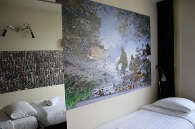 a bedroom with a large painting on the wall at Bicycle Hotel Amsterdam in Amsterdam
