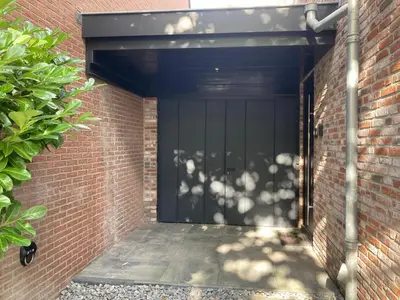 a black garage door in a brick building at The Oyster House With Private Parking in Zandvoort