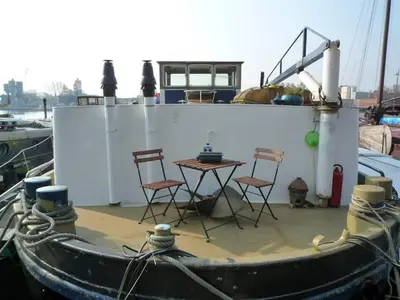 a table and chairs on a boat in the water at Houseboat Captain's Quarters in Harbour Amsterdam in Amsterdam