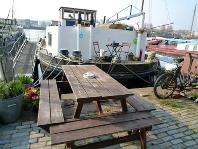 a picnic table and a bike next to a boat at Houseboat Captain's Quarters in Harbour Amsterdam in Amsterdam