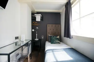 a small bedroom with a bed and a desk at Quentin Leidse Square Hotel in Amsterdam