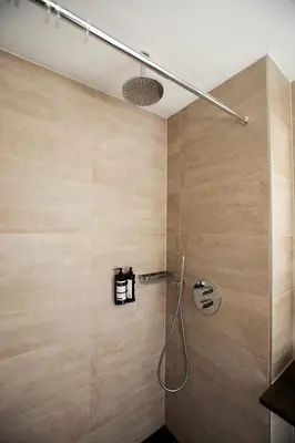 a shower in a bathroom with wooden walls at Quentin Leidse Square Hotel in Amsterdam